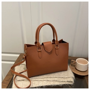 Close-up of a brown pebble leather tote bag on a knitted scarf with coffee cup detail