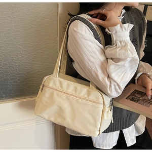 Detail view of cream canvas tote bag with front zipper pocket on model's shoulder