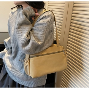 Detail shot of a khaki canvas tote bag worn with a sweater, showing size and casual style