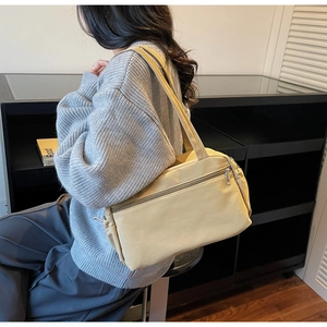 Side view of beige canvas tote bag with front zipper pocket shown on female model