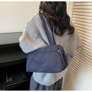 Detail of dark blue nylon tote bag with front zipper pocket on casual sweater