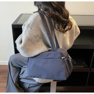 Detail of dark blue nylon shoulder bag with multiple zippers and wide strap for daily use