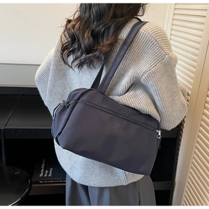 Detail of minimalist dark grey-blue canvas tote bag shown worn on shoulder with knit sweater