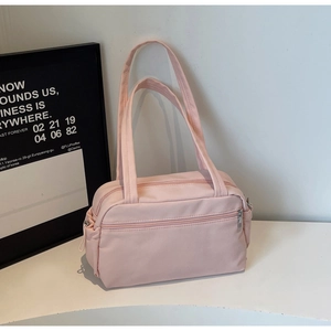 Detailed view of light pink nylon tote bag with zipper pocket on a white surface