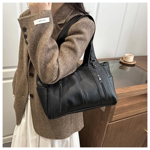 Detail of black large capacity tote bag featuring soft lychee texture and vertical zippers