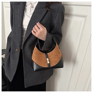Detail of a brown suede and black leather patchwork handbag with gold buckle