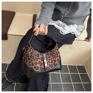 Detail of leopard print hobo bag with black leather trim and golden twist lock closure