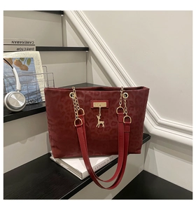 Detail of burgundy leopard embossed tote bag with gold chain strap and deer charm