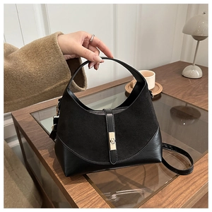 Detail of a vintage black bucket bag with mixed textures, metal clasp, and handle