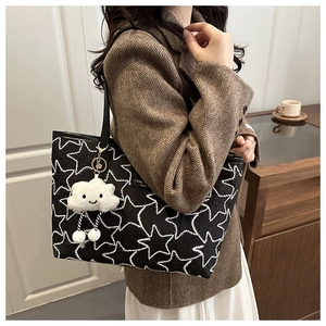 Detail of black star quilted tote bag with cute white cloud plush pendant accessory