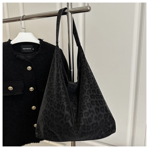 Détail du sac cabas noir à motif léopard avec bandoulière large sur un support