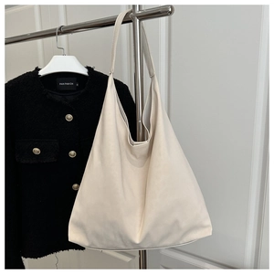 Détail d'un sac cabas en cuir crème sur cintre avec une veste noire élégante