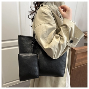 Detail of black faux leather tote bag with matching zippered pouch and knotted strap detail