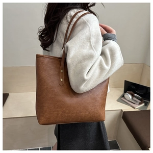 Close-up of brown leather tote bag texture with gold rivet details on shoulder strap