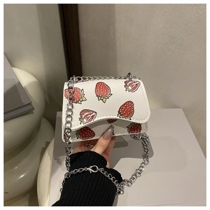 Close-up of mini white crossbody bag with red strawberry print and silver chain strap