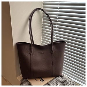 Detail of dark brown pebble leather tote bag with debossed fashion and bags text