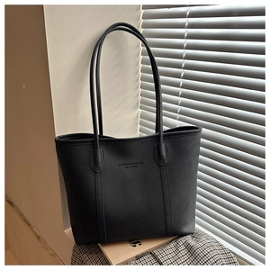 Close-up of litchi texture black tote bag with embossed logo on a lifestyle background