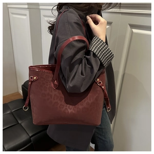 Side view of dark burgundy leopard print tote bag with gold hardware and matte finish