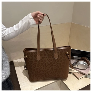 Detail of vintage leopard print tote bag featuring matte texture and gold metal accents