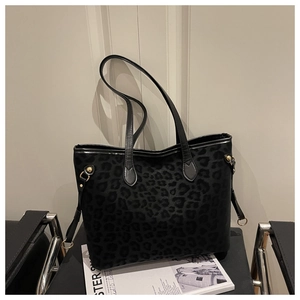 Detailed view of black leopard print tote bag with leather straps on a modern chair