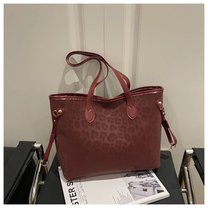 Macro detail of wine red leopard print tote bag with matte texture and gold hardware
