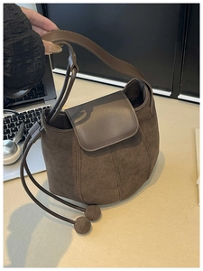 Detail of dark brown crossbody bag with matte texture and dual spherical decorative pendants