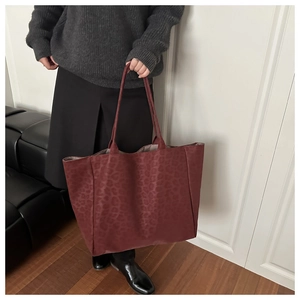 Deep burgundy leopard print tote bag with large capacity shown on model shoulder