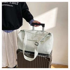 Détail du sac de voyage vert menthe avec passant pour bagage sur valise argentée