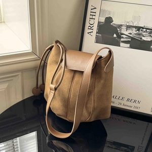 Brown suede pumpkin bucket bag with sleek leather straps and drawstring details