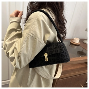 Detail of black leopard print underarm bag with gold metal lock on female model