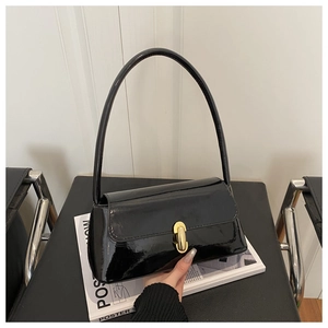 Close-up of the glossy black faux leather shoulder bag with a gold capsule metal clasp