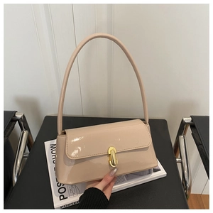 Detail of glossy beige patent leather bag with gold buckle and slim shoulder strap