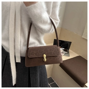Détail de la texture léopard sur sac en daim marron avec fermoir en métal doré