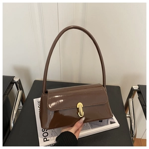 Detail of glossy brown handbag with golden twist-lock buckle and smooth mirror finish