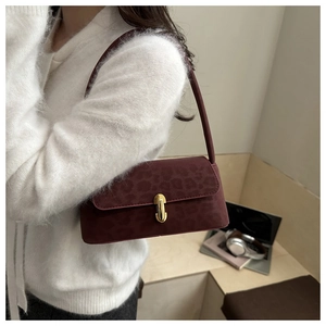 Gros plan du sac sous l'aisselle rétro bordeaux avec boucle dorée sur cardigan blanc