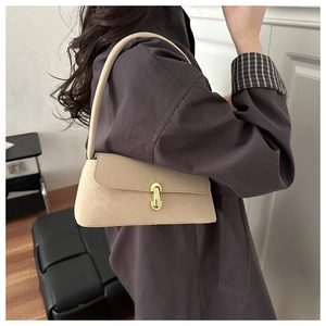Side view of model wearing a beige suede baguette shoulder bag with gold oval clasp