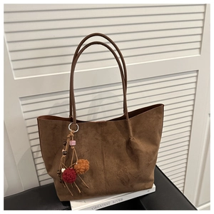 Detail of large brown suede tote bag with colorful plush ball and wooden bead charms