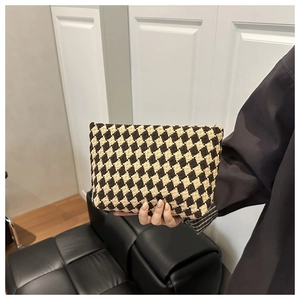 Detail of checkered woven texture and smooth zipper on a beige and brown makeup bag