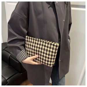 Detail of a vintage-style checkered woven clutch bag in dark coffee and beige finish