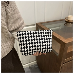 Close-up of black and white checkered knit handbag with thick woven texture and zipper