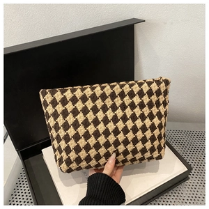 Detail of a luxury woven clutch bag with brown diamond pattern on a gray background