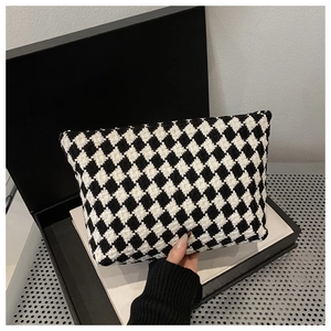 Detail of checkered woven fabric texture on a monochrome handheld cosmetic bag