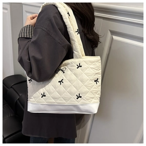 Detail van crème gewatteerde shopper met zwart strikborduurwerk en brede schouderriem