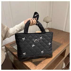 Detail van de gewatteerde shopper met witte strikborduursels en 3D-strikdecoratie