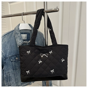 Detail van zwarte gewatteerde shopper met wit strikborduursel en leren bodemafwerking