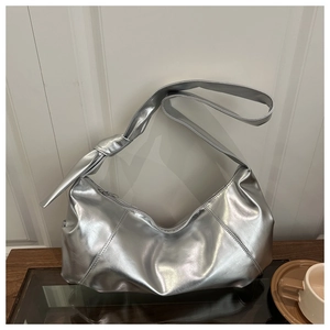 Detail of silver crescent bag featuring large decorative shoulder strap knot and metallic finish