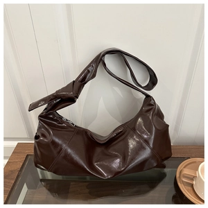 Detail of dark brown glossy leather hobo bag with unique knotted strap and quilted finish