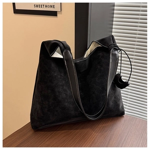Close-up of black tote bag featuring white contrast stitching and vintage faux leather texture