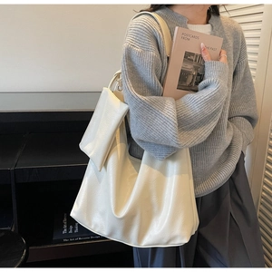 Detail of cream white large leather tote bag with a small matching purse on grey sweater