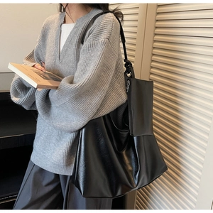 Detail of black leather tote bag with smooth texture and matching small zipper pouch